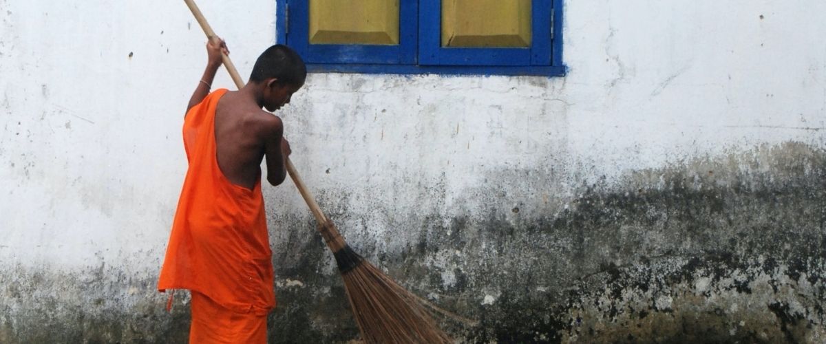 Monk sweeps the street in front of his home in Cambodia.